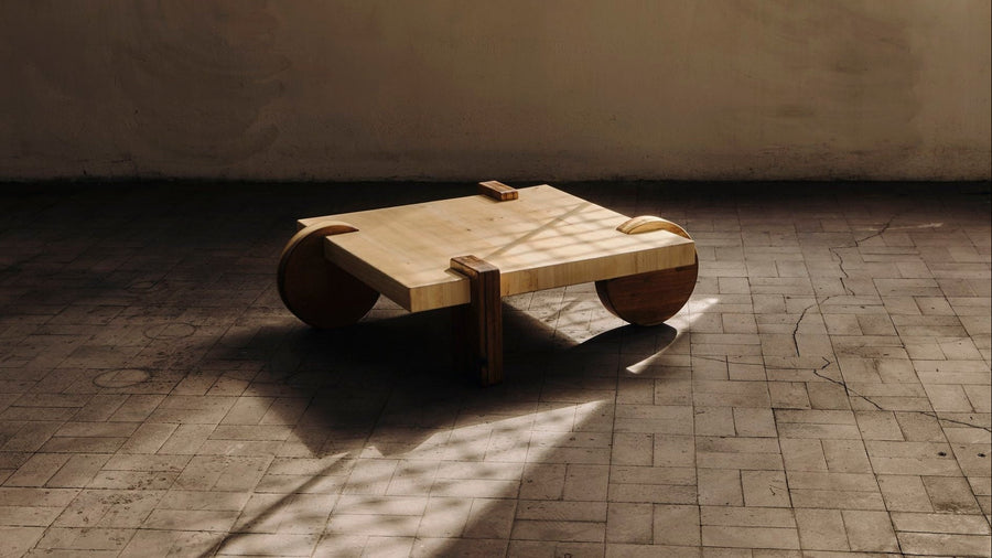 Table basse en bois déchus dans un intérieur, lumière rasante sur sol carrelé